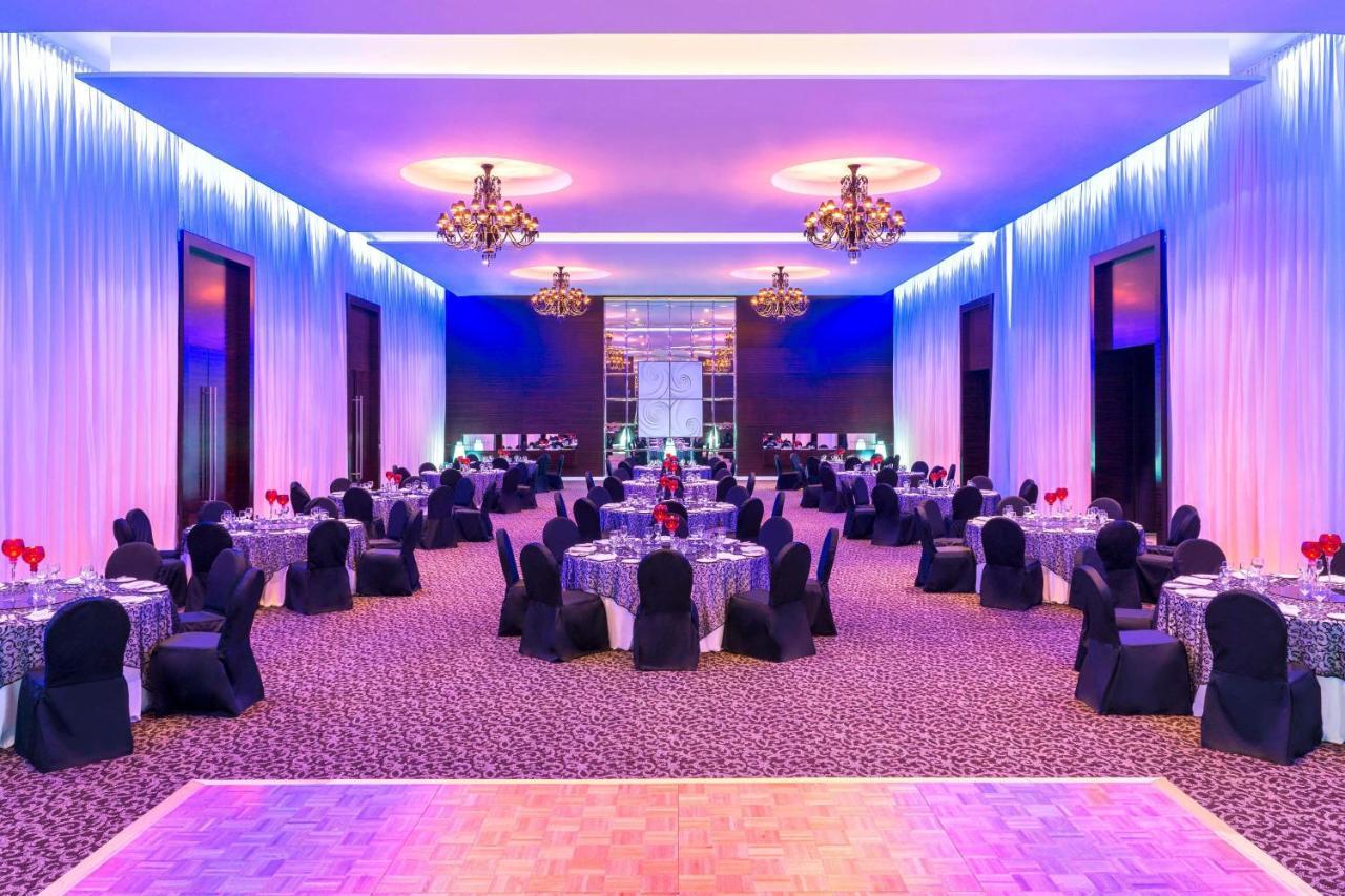 เลอ เมริเดียน ดูไบ โฮเต็ล แอนด์ คอนเฟอเรนซ์ เซ็นเตอร์ Hotel ภายนอก รูปภาพ The photo shows a spacious and elegantly decorated banquet hall. The room features several round tables, each set with tablecloths and adorned with centerpieces, likely for an event or celebration. The chairs are covered in black fabric, adding to th