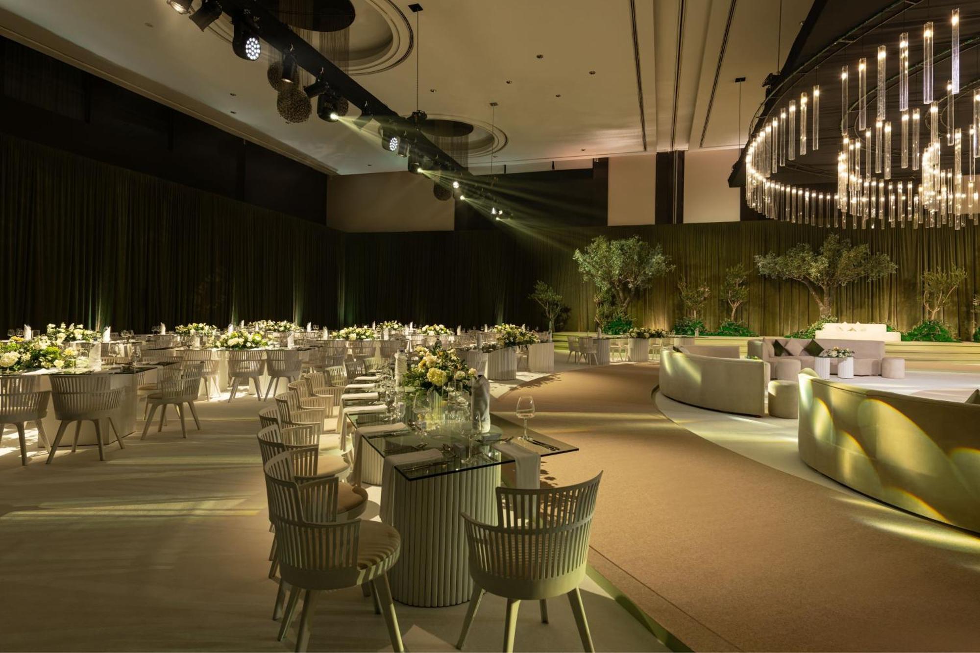 เลอ เมริเดียน ดูไบ โฮเต็ล แอนด์ คอนเฟอเรนซ์ เซ็นเตอร์ Hotel ภายนอก รูปภาพ The image depicts a sophisticated indoor event space, likely set up for a formal gathering or celebration. The room features elegantly arranged round tables with white tablecloths, each adorned with floral centerpieces. The lighting is soft and ambie